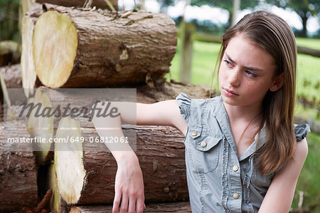 Teenage girl leaning on logs in  forest