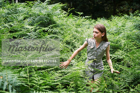 Teenage girl walking through bracken in forest