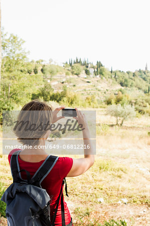 Woman taking photo of rural scene on camera phone