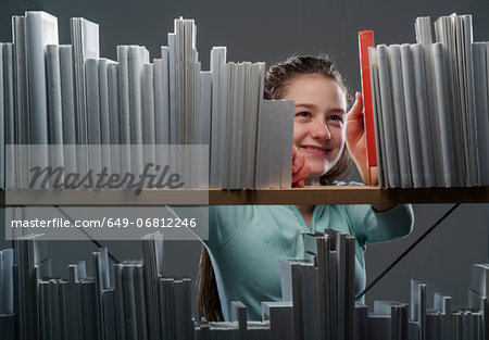 Girl choosing red book from bookshelf