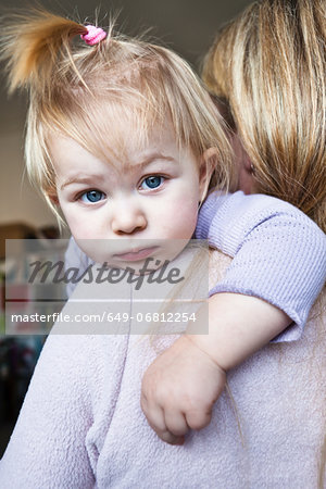 Mother holding toddler daughter over shoulder