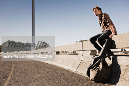 Young man waiting for a ride at the side of a road Young man waiting for a ride at the side of a road