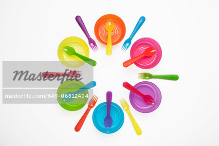 Colourful plastic plates, cups, bowls, spoons and forks