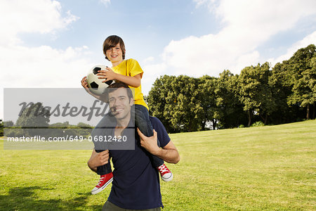 Father carrying son on shoulders with football