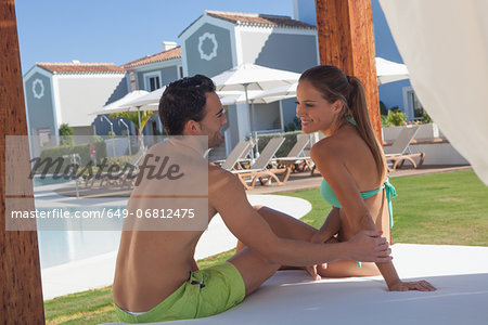 Young couple sitting on sunlounger at holiday resort