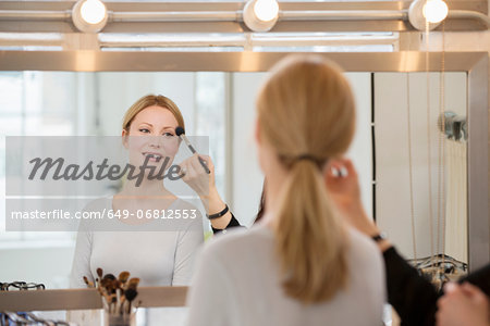 Mid adult woman having make-up applied