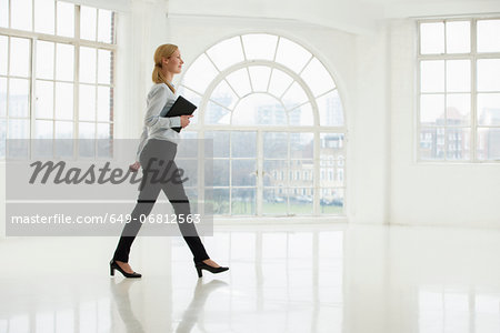 Businesswoman walking in sparse white room Businesswoman walking in sparse white room