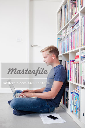 Young man sitting on floor using laptop