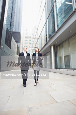 Businessman and businesswoman walking past office buildings