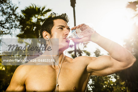 Young man exercising in forest drinking mineral water