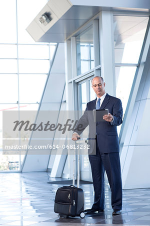 Mature businessman with digital tablet and suitcase