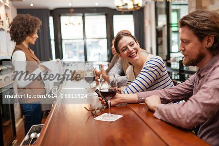 Woman and man at bar chatting and checking cell phone