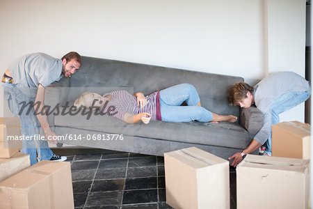 Young woman moving house on sofa being carried by men