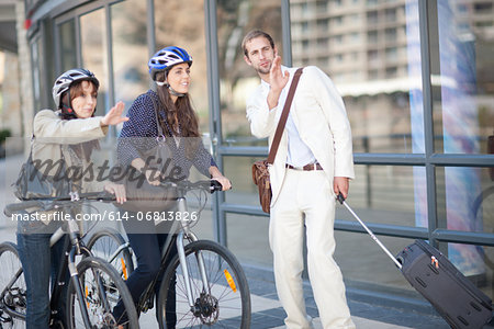 Young women with bicycles asking young man for directions