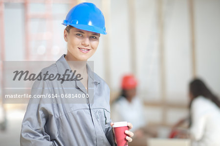 Smiling female construction worker with coffee