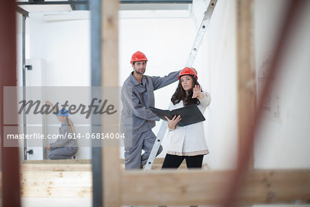 Female architect discusses plans with laborer on construction site