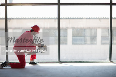Laborer kneeling in front of window with circular saw