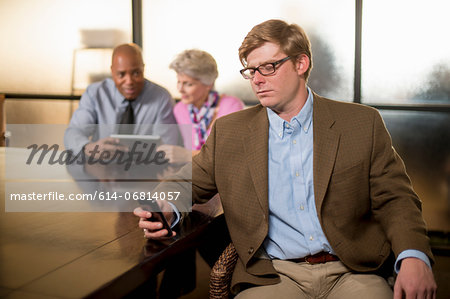 Young man using cell phone with colleagues in background