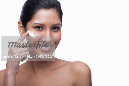 Young woman applying face cream