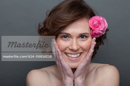 Young woman with flower in hair and hands on face