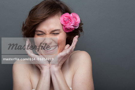 Young woman with flower in hair and hands on face