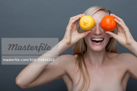 Young woman covering eyes with orange and lemon