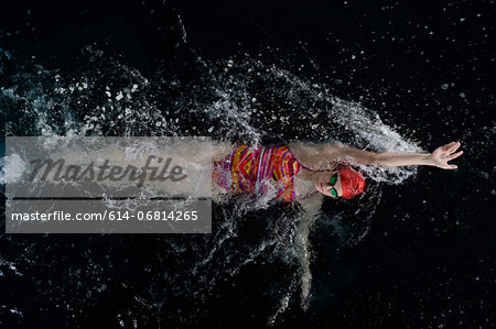 Teenage girl doing backstroke in swimming pool