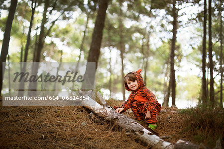 Portrait of male toddler wearing tiger suit playing in woods