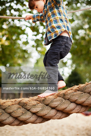 Male toddler crossing rope bridge