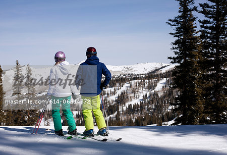 Young couple holding hands at top of ski run