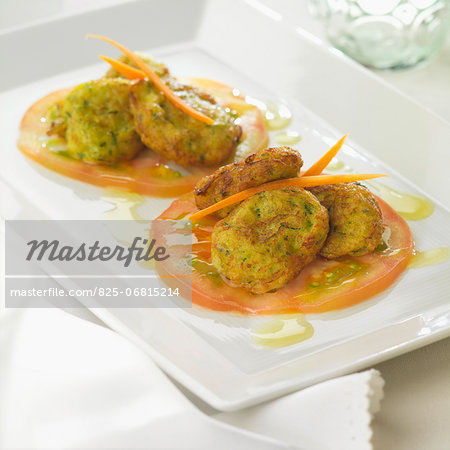 Zucchini croquettes on thinly sliced tomatoes