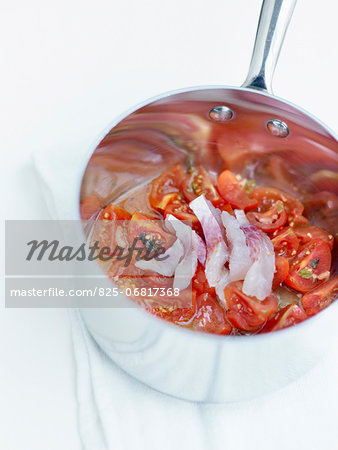 Tomatoes and oregano with thinly sliced raw red mullets in a saucepan