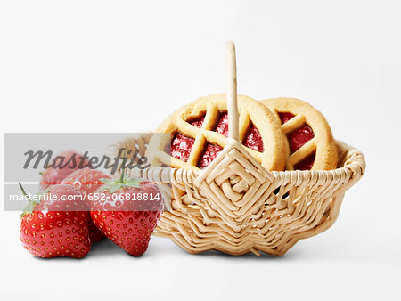 Strawberry jam cookies in a basket and fresh strawberries