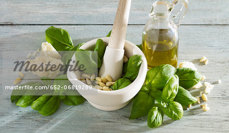 Preparing pesto with basil,pine nuts,parmesan and olive oil in a mortar