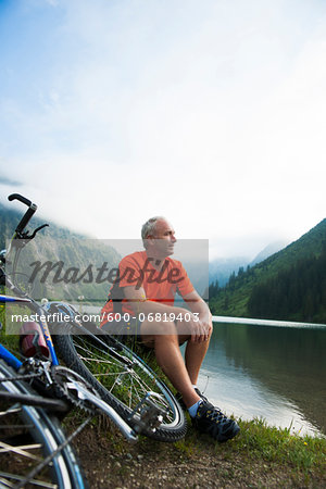 Mature Man Sitting by Lake with Mountain Bike, Vilsalpsee, Tannheim Valley, Tyrol, Austria