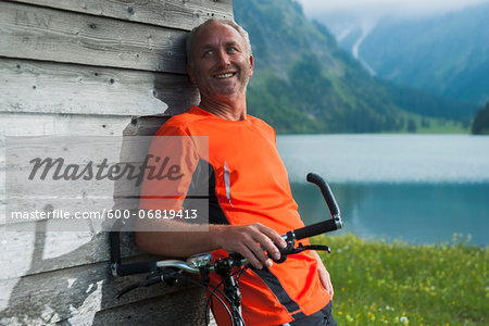 Mature Man leaning against Wooden Building with Mountain Bike, Vilsalpsee, Tannheim Valley, Tyrol, Austria