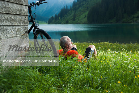 Mature Man with Mountain Bike Relaxing by Lake, Vilsalpsee, Tannheim Valley, Tyrol, Austria