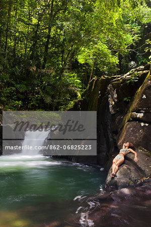 Dominica, Bense. A young woman lays on the rocks at La Chaudiere Pool. (MR).