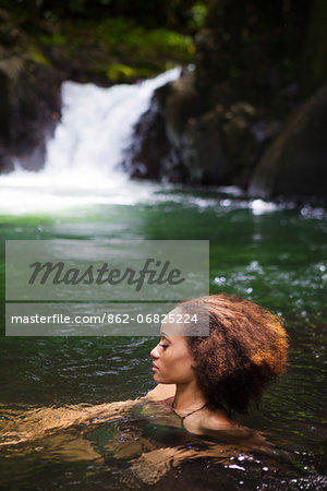 Dominica, Bense. A young woman relaxes in the natural plunge pool at La Chaudiere. (MR). Dominica, Bense. A young woman relaxes in the natural plunge pool at La Chaudiere. (MR).