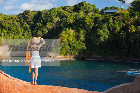 Dominica, Calibishie. A young woman looks out from the red rocks at Pointe Baptiste. (MR).