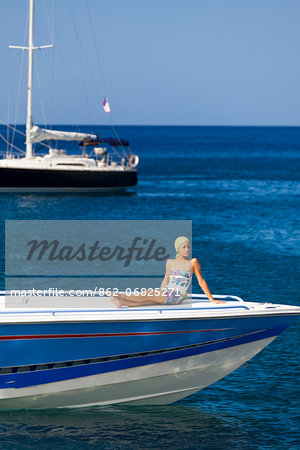 Dominica, Roseau. A young woman sits on the foredeck of a Powerboat near Roseau. (MR). Dominica, Roseau. A young woman sits on the foredeck of a Powerboat near Roseau. (MR).