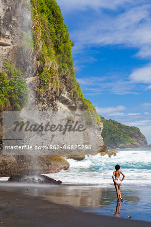 Dominica, Riviere Cyrique. A young woman stands looking at the waterfall at Wavine Cyrique. (MR).