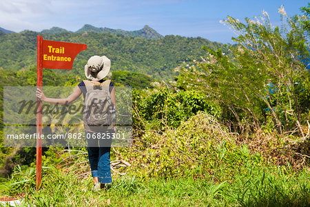 Dominica, Riviere Cyrique. A young woman stands by a sign at the start of the trail to Wavine Cyrique. (MR).