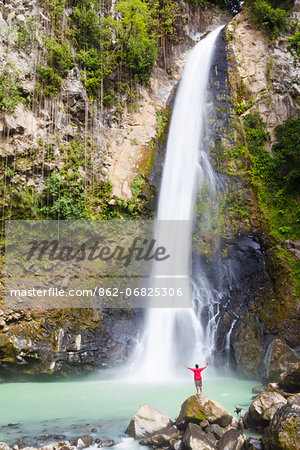 Dominica, Delices. A man stands at the base of Victoria Falls, one of the tallest and most spectacular waterfalls on Dominica. (MR). Dominica, Delices. A man stands at the base of Victoria Falls, one of the tallest and most spectacular waterfalls on Dominica. (MR).