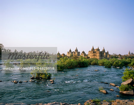 Asia, India, Madhya Pradesh, Orchha.  Chhatris, cenotaphs to Orchha's rulers with the Betwa River running in the foreground.