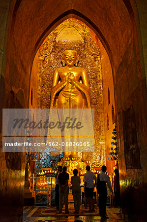 Myanmar, Burma, Mandalay Region, Bagan. In the heart of Ananda Pahto, or Ananda Temple, a gilded teak statue of the Buddha with its Dharmachakra mudra, or hand gesture, indicating teaching which reflects his first historical sermon on the cosmic order.