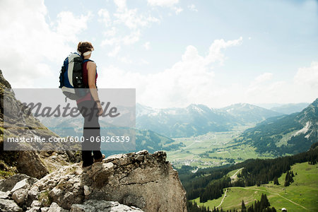 Mature woman standing on cliff, hiking in mountains, Tannheim Valley, Austria