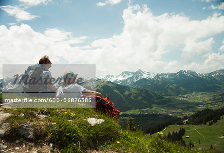 Backview of mature couple sitting on grass, hiking in mountains, Tannheim Valley, Austria Backview of mature couple sitting on grass, hiking in mountains, Tannheim Valley, Austria
