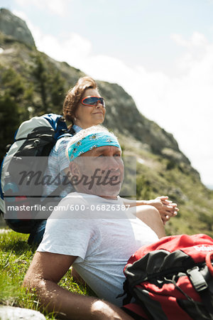 Close-up of mature couple sitting on grass, hiking in mountains, Tannheim Valley, Austria Close-up of mature couple sitting on grass, hiking in mountains, Tannheim Valley, Austria