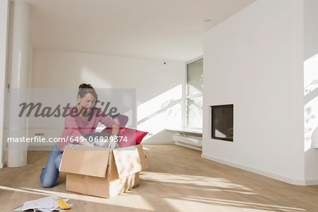 Woman unpacking cardboard box in empty room